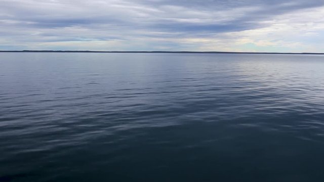 The Strait of Magellan filmed from a boat at dawn. In the background is Punta Arenas city. Calm and no wind