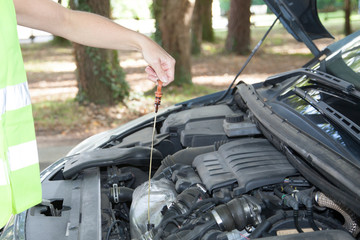 woman broke down with her car checking the oil level