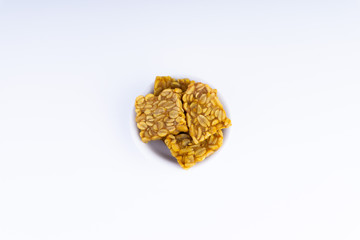 Fried tempeh or soybean cake in white bowl over a white background. It is made by fermentation process that binds soybeans into a cake form.