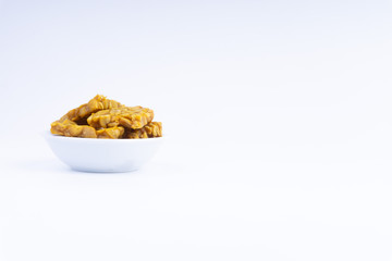 Fried tempeh or soybean cake in white bowl over a white background. It is made by fermentation process that binds soybeans into a cake form.