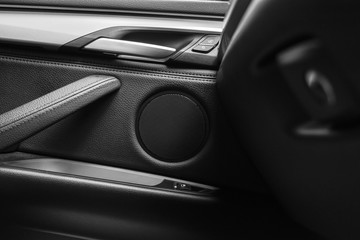 Door handle with Power window control buttons of a luxury passenger car. Black leather interior of the luxury modern car. Modern car interior details. Car detailing. Black and white