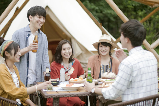 グランピングテントの前で食事をする若者たち