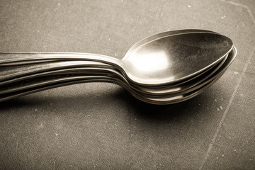 Lot of metal cutlery on a black background. Selective focus. Shallow depth of field. Toned