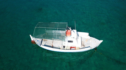 Aerial drone bird's eye view of traditional fishing boat in port of Mykonos in sapphire clear waters, Cyclades, Greece
