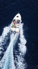 Aerial birds eye view from drone of boat cruising in high speed in turquoise water, island of Mykonos, Cyclades, Greece