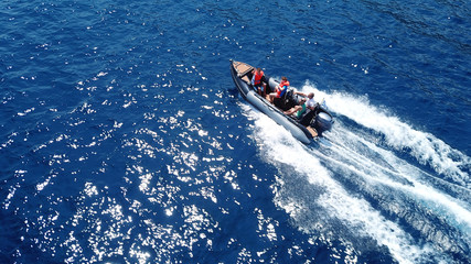 Aerial bird's eye view of inflatable rib boat cruising in high speed in deep blue mediterranean sea