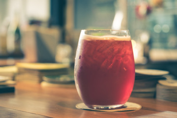 Red beverage on a wooden table in a restaurant. (vintage tone)