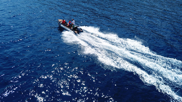Aerial bird's eye view of inflatable rib boat cruising in high speed in deep blue mediterranean sea