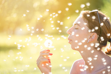 Cute girl blowing dandelion