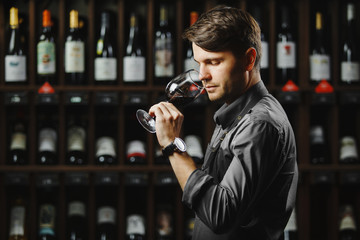 Bokal of red wine on background, male sommelier appreciating drink