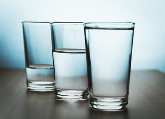 studio shot of three water glasses each one have more water than the other