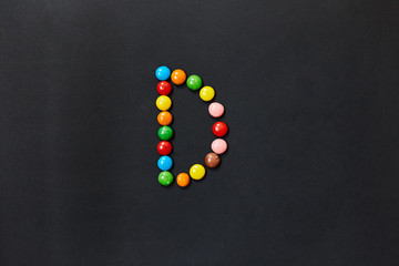 English Alphabet made of colored candies. The letter D.