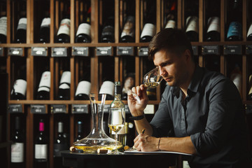 Sommelier degustating white wine poured in glass