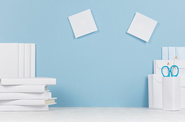 Creative workplace for designers and students - white office stationery, blank stickers on table and blue background. Back to school background with copy space.