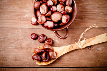 Chestnuts in a clay bowl on the old wooden background. Toned