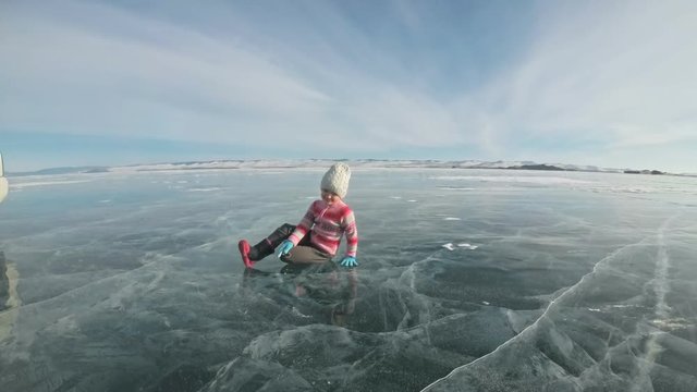 Girl is training practice yoga in winter. Children is do stretching and meditation on ice in nature. Kid practices yoga, doing twine with cracks ice. Child do sport fitness in outdoor. Background
