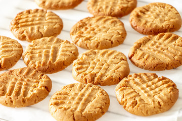 Delicious homemade peanut butter cookies on cooling rack. White wooden background. Healthy snack concept.