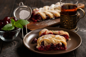 Homemade cherry puff pastry braid, on blue wooden background.