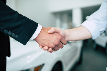 Cropped photo of handshake in dealership on white car background