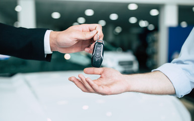 Take the keys. Close up photo of the transfer of keys from the new machine to the buyer against the...