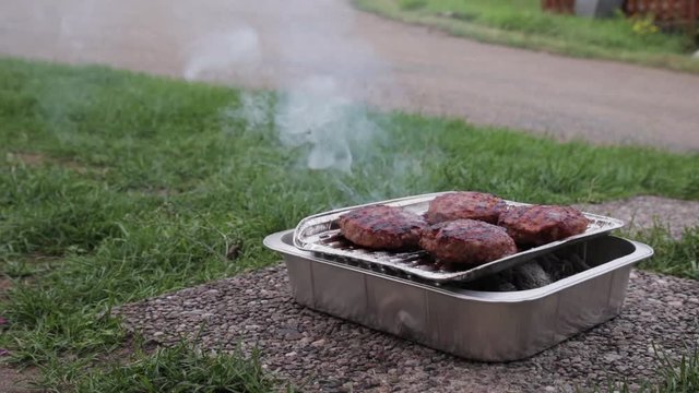 A Timelapse of Four hamburgers on a Disposable Barbecue