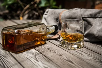 Papier Peint photo Alcool glass of whiskey and a bottle of whiskey on a wooden background