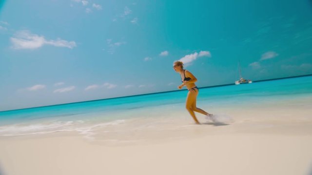 Girl running in surf and splashing water, Klein Curacao