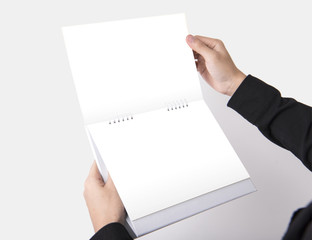 Hand holding Blank paper spiral calendar for mockup template advertising and branding background.