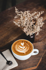 Cup of hot latte art coffee on wooden table