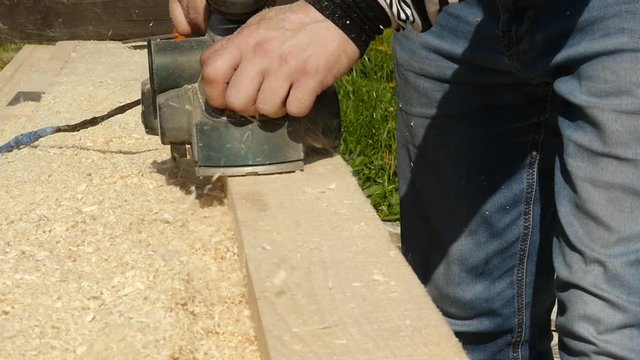 man working on a wood planing machine. Chips fly in different side from the planer