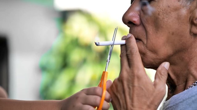 Old man is smoking cigarette and Children use scissors to cut cigarette. Slow Motion.  A lot of smoke around. Smoking as harmful to society. stop cigarette