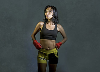 Obraz premium portrait of sporty and fit fighter Asian Chinese woman using wrist wraps training mma fight sport or boxing workout looking dangerous in badass pose