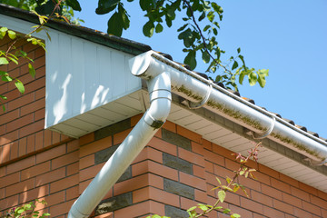 Close up on white plastic rain gutter. House roof guttering repair.