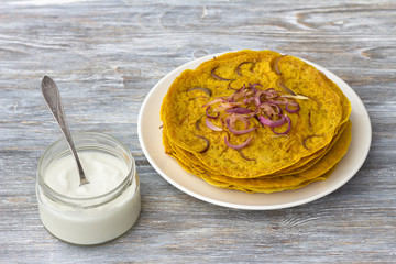 Pancakes with onion, curry and yogurt sauce. on a wooden table. selective focus. delicious homemade food