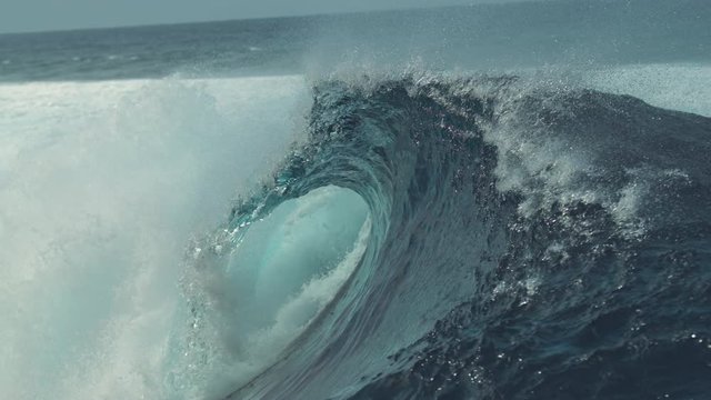 SLOW MOTION, CLOSE UP: Big splashing barrel wave rushes towards the coast of an exotic island in the sunny Pacific. Glassy droplets of water shine in the summer sun as big tube wave crashes wildly.