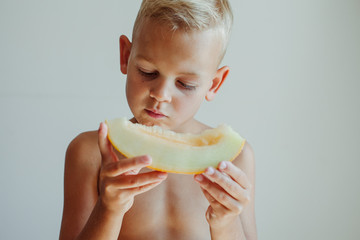 A little boy eats melon