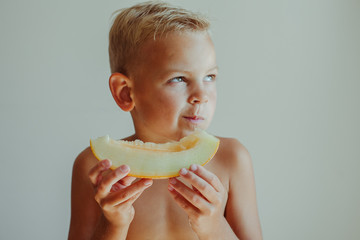 A little boy eats melon