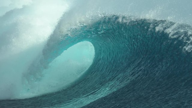 SLOW MOTION, CLOSE UP: Forceful barrel wave splashes beautiful crystal clear water everywhere around the sunny coast of Tahiti. Amazing shot of a large tube wave right when it breaks and crashes.