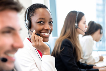 Smiling beautiful African American woman working in call center with diverse team - Powered by Adobe