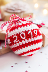 Christmas and New Year 2019 background with crocheted handmade ball, presents and decorations for Christmas tree. Holiday background with stars confetti and light bulbs. Place for text.