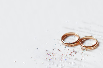 Golden wedding rings on paper invitation with shiny rhinestones. Wedding details, symbol of love...
