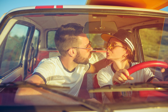 Laughing romantic couple sitting in car while out on a road trip at summer day