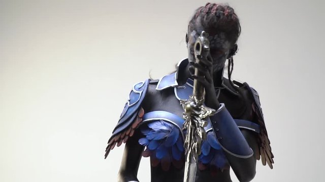 Slender drow woman relaxes posing with fantasy sword, slow motion