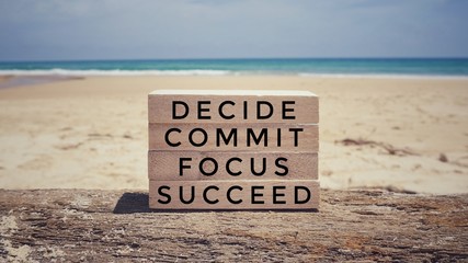 Motivational and inspirational quote - ‘ Decide, commit, focus, succeed’ on a wooden blocks. With vintage styled background.