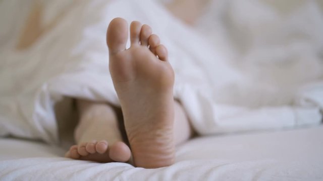 Woman in bare legs and feet on the bed