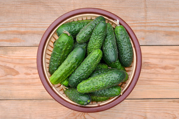Basket with many fresh cucumbers on wooden background