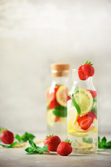 Citrus and strawberry lemonade with mint, lemon on grey background. Detox drink. Summer fruit infused water. Copy space.