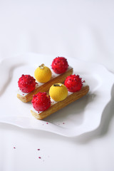 Contemporary Mango Strawberry Eclair, on white background.
