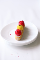 Contemporary Mango Strawberry Eclair, on white background.
