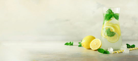 Detox water with mint, lemon on grey background. Banner with copy space. Citrus lemonade. Summer fruit infused water. Refreshing homemade cocktail, selective focus. - obrazy, fototapety, plakaty